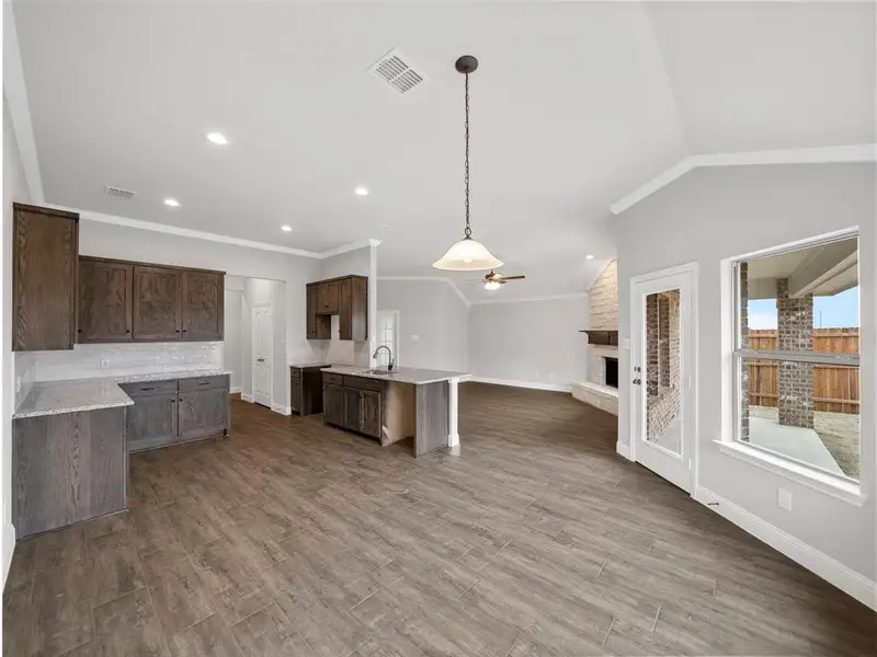 Kitchen featuring a fireplace, open floor plan, a ceiling fan, visible vents, and a sink Kitchen featuring a fireplace, open floor plan, a ceiling fan, visible vents, and a sink