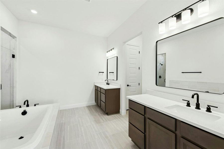 Full bathroom featuring two vanities, a marble finish shower, a soaking tub, and recessed lighting