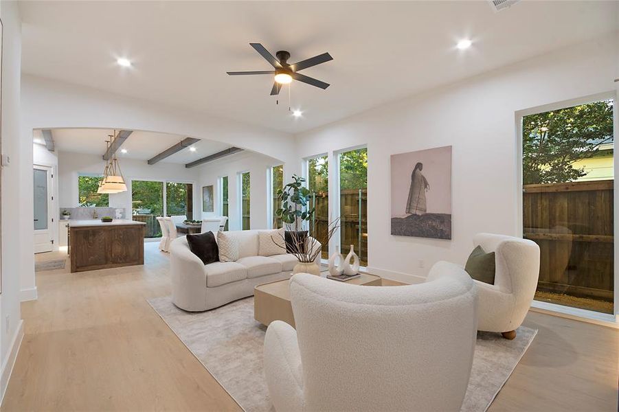 Living area featuring beamed ceiling, light wood-type flooring, recessed lighting, ceiling fan, and arched walkways