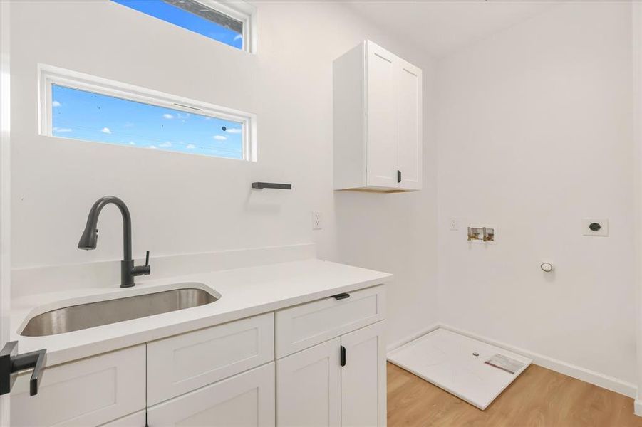 Laundry area with light wood-style floors, hookup for a washing machine, cabinet space, hookup for an electric dryer, and hookup for a gas dryer Laundry area with light wood-style floors, hookup for a washing machine, cabinet space, hookup for an electric dryer, and hookup for a gas dryer