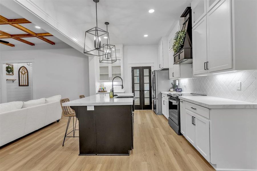Light and Bright Kitchen featuring white cabinetry, a breakfast bar area, black french doors leading to walk-in pantry. Light and Bright Kitchen featuring white cabinetry, a breakfast bar area, black french doors leading to walk-in pantry.
