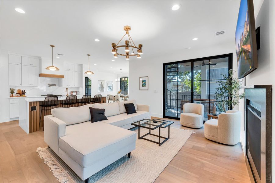 Living room with a chandelier, recessed lighting, light wood-style floors, and a fireplace Living room with a chandelier, recessed lighting, light wood-style floors, and a fireplace