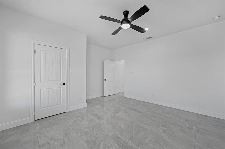 Unfurnished bedroom with ceiling fan and light tile patterned flooring