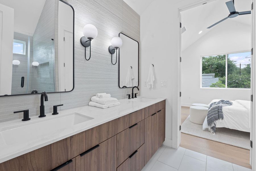 Bathroom with double vanity, vaulted ceiling, plenty of natural light, tile patterned flooring, and a shower stall