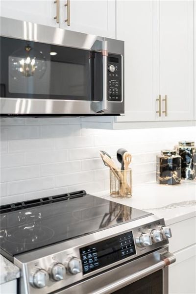 Interior details featuring 42' inch white upper cabinets, appliances with stainless steel finishes, light stone counters, and tasteful backsplash. Not actual home. Photos of Model Home.