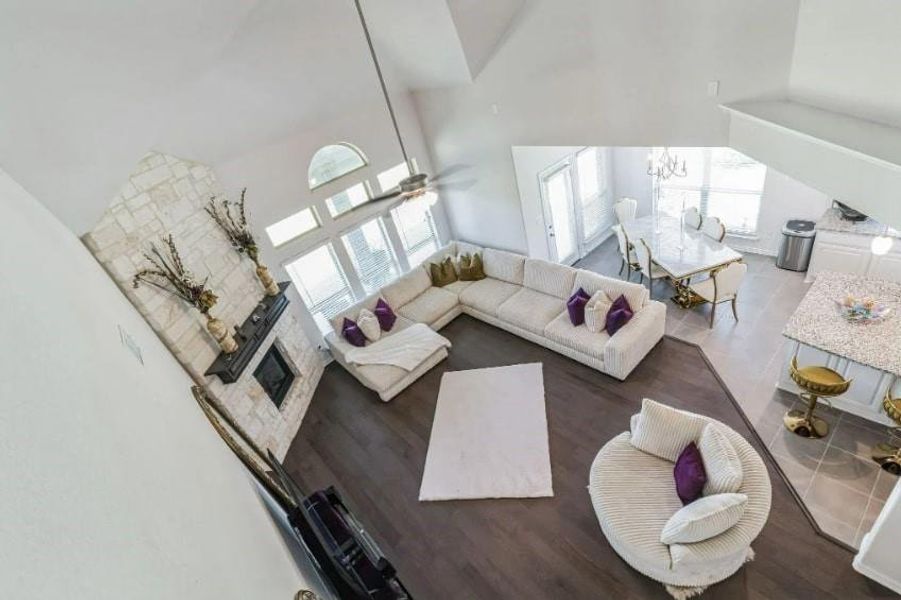 Living room featuring a high ceiling, ceiling fan with notable chandelier, and wood-type flooring