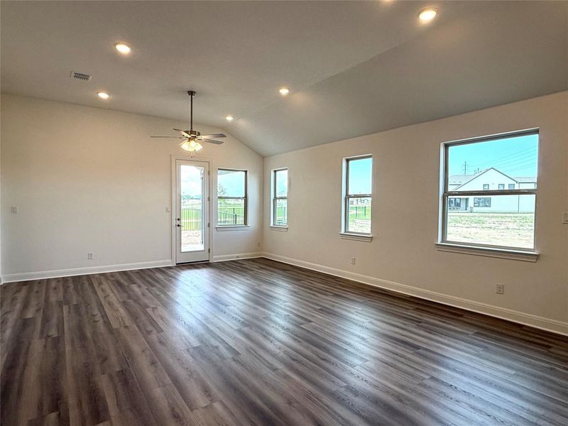 Empty room with plenty of natural light, baseboards, vaulted ceiling, dark wood-type flooring, and recessed lighting Empty room with plenty of natural light, baseboards, vaulted ceiling, dark wood-type flooring, and recessed lighting