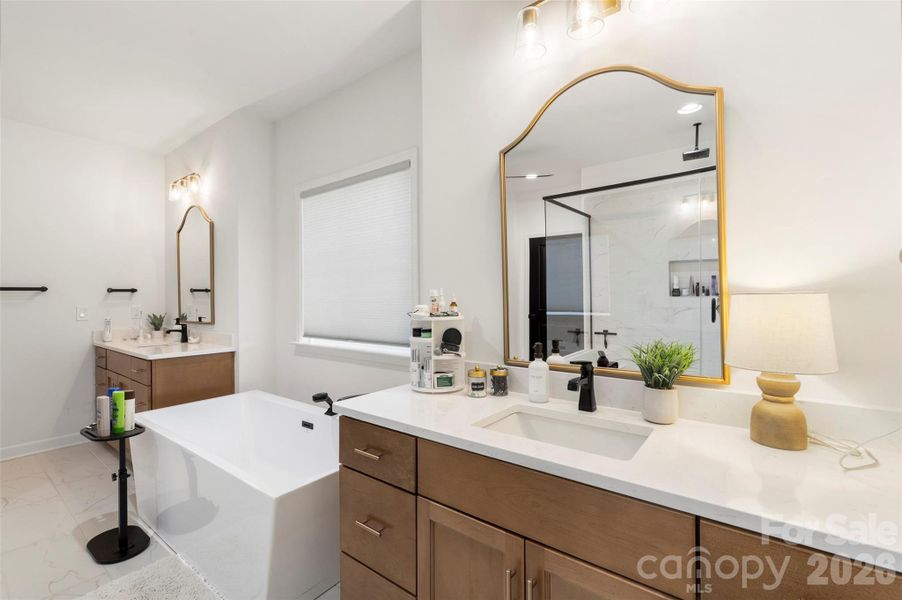 Spacious and inviting Primary bathroom with stand alone tub and dual oversized vanities, custom lighting and gold framed mirrors. Spacious and inviting Primary bathroom with stand alone tub and dual oversized vanities, custom lighting and gold framed mirrors.