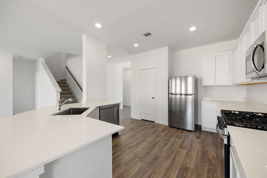 Sleek design kitchen feautures white cabinets, quartz countertops, stainless steel appliances.