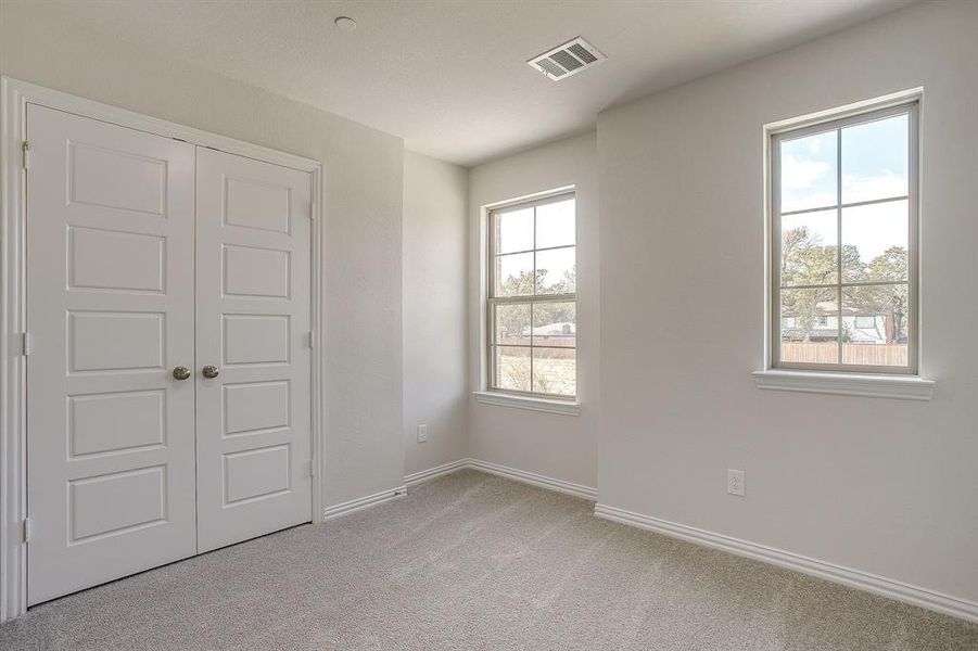 Unfurnished bedroom with light colored carpet and a closet