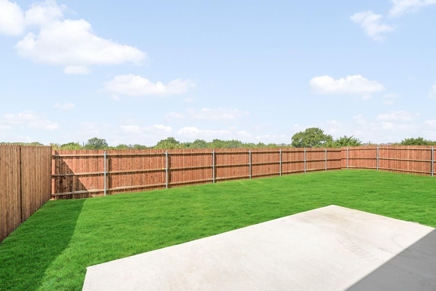 Backyard with green grass lawn, concrete patio, and full wood privacy fence