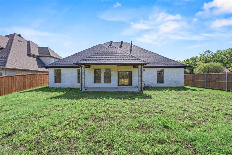 Expansive backyard featuring a covered patio, brick exterior, dark asphalt shingle roof, and a wood privacy fence Expansive backyard featuring a covered patio, brick exterior, dark asphalt shingle roof, and a wood privacy fence