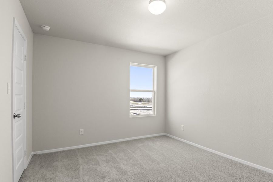 Image of a bedroom with light grey walls, tan carpeting and a window