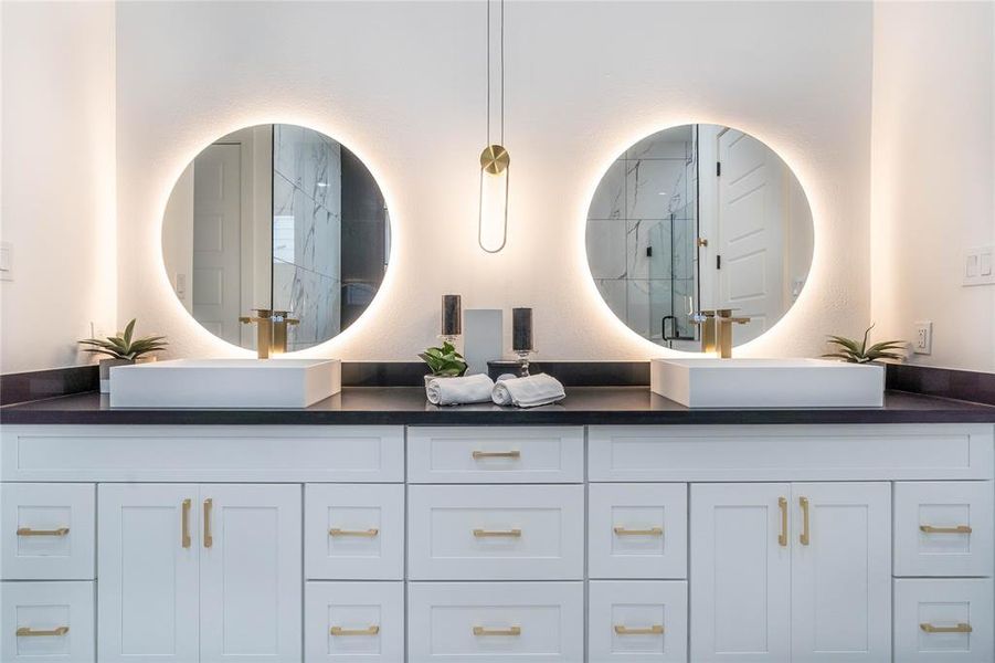 The primary bathroom boasts a spacious vanity with ample storage and adjustable LED mirrors.