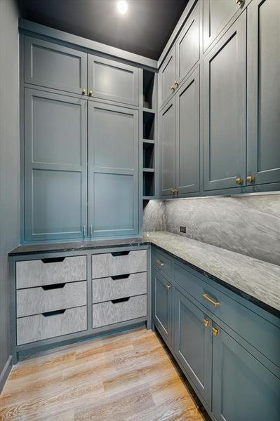 Elegant pantry area with custom cabinetry and stone countertops, offering ample storage space and a sleek design.