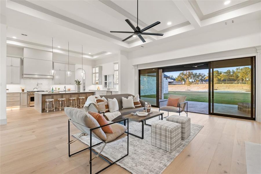 Living area with light wood-style flooring, recessed lighting, a ceiling fan, and a tray ceiling Living area with light wood-style flooring, recessed lighting, a ceiling fan, and a tray ceiling