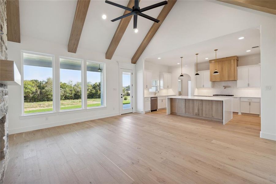 Unfurnished living room featuring ceiling fan, beam ceiling, light hardwood / wood-style flooring, and high vaulted ceiling