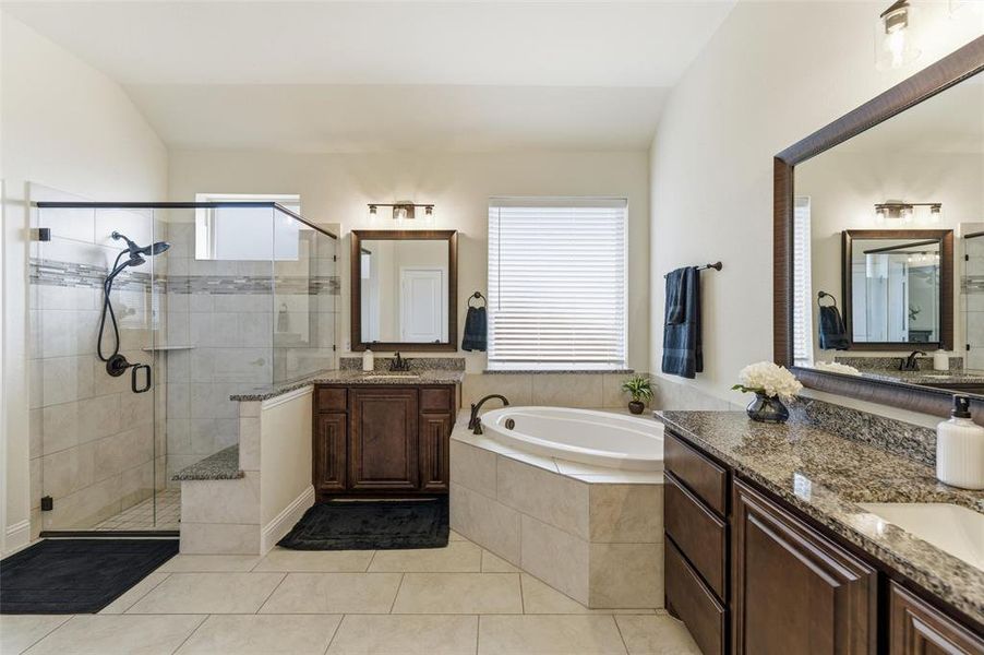 Bathroom featuring a stall shower, two vanities, a garden tub, and light tile patterned floors