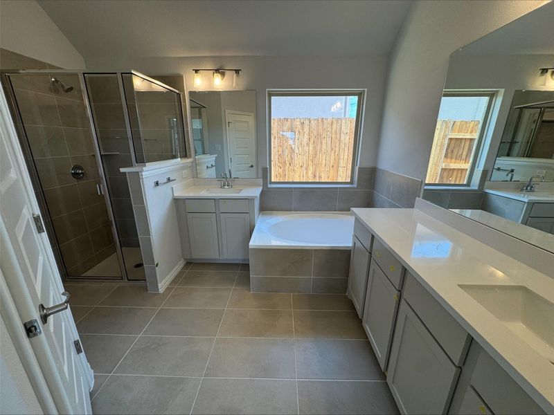 Bathroom featuring tile patterned flooring, a stall shower, two vanities, a bath, and vaulted ceiling Bathroom featuring tile patterned flooring, a stall shower, two vanities, a bath, and vaulted ceiling