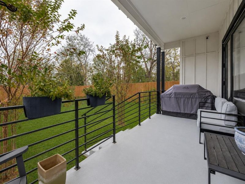 Covered outdoor patio featuring a smooth concrete floor and a contemporary black metal railing Covered outdoor patio featuring a smooth concrete floor and a contemporary black metal railing