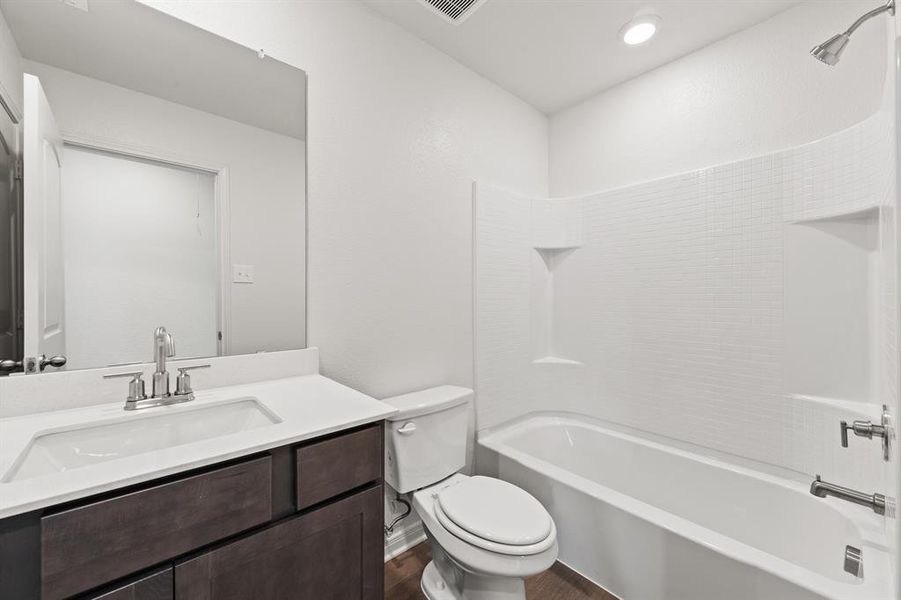 Full bathroom with wood-style floors, tub / shower combination, vanity, and toilet