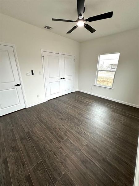 Unfurnished bedroom featuring dark wood-type flooring, ceiling fan, and a closet