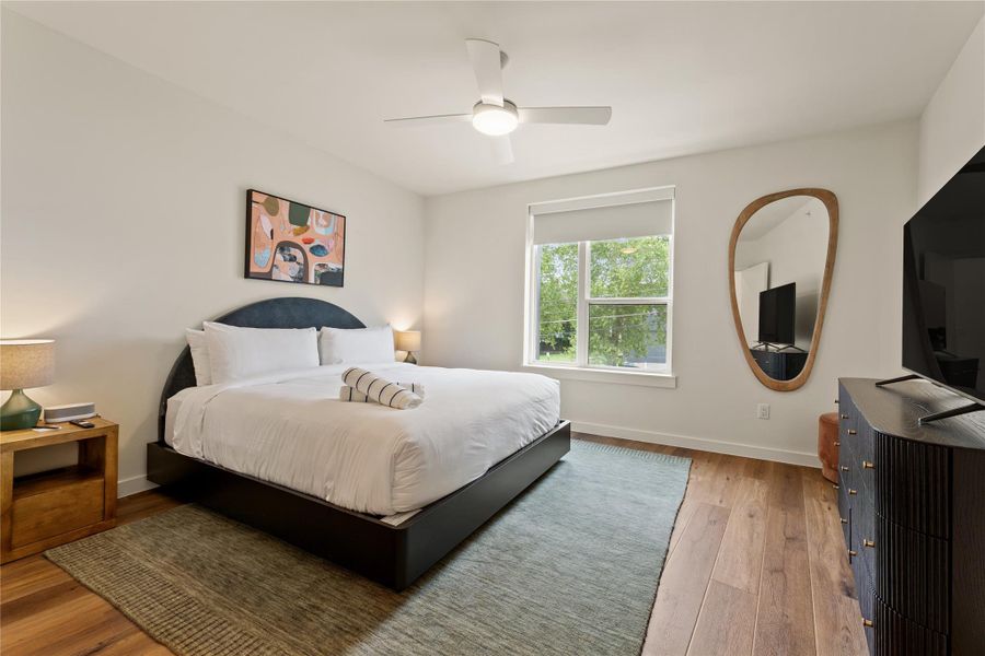 Rich hardwood floors and a large window frame pleasant views in this restful bedroom.
