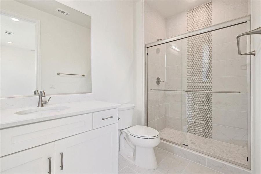 Bathroom featuring tile floors, walk in shower, vanity, and toilet