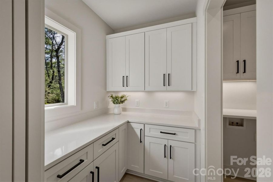 The walk-in pantry has a charming window and lots of cabinetry for storage and tons of quartz counter space to work. There is a door into the laundry room on the right. The walk-in pantry has a charming window and lots of cabinetry for storage and tons of quartz counter space to work. There is a door into the laundry room on the right.