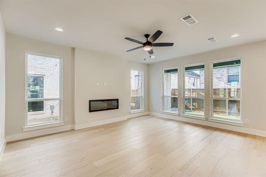 Unfurnished living room featuring a glass covered fireplace, light wood-style flooring, recessed lighting, and a ceiling fan