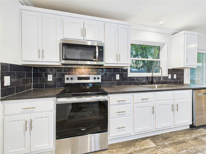 Crisp white cabinetry paired with a bold black subway tile backsplash and contrasting island.