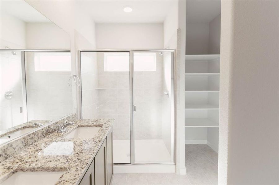 Bathroom featuring tile patterned flooring, double vanity, and an enclosed shower