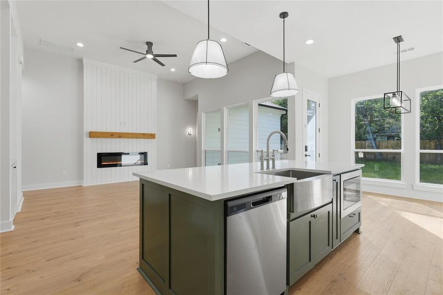 Kitchen island featuring a stainless steel farm sink, integrated dishwasher, and under-counter microwave drawer Kitchen island featuring a stainless steel farm sink, integrated dishwasher, and under-counter microwave drawer