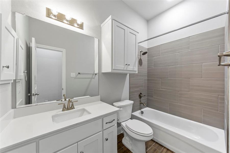 Full bathroom with toilet, hardwood / wood-style floors, vanity, and tiled shower / bath