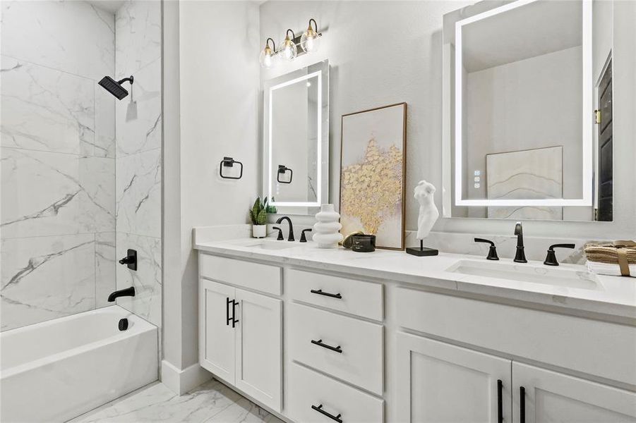 Bathroom featuring shower / washtub combination, double vanity, and light marble finish flooring Bathroom featuring shower / washtub combination, double vanity, and light marble finish flooring