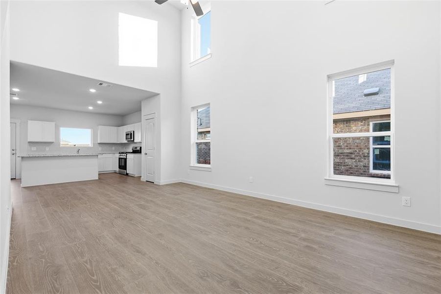 Open-concept living space featuring high ceilings, wood-finish flooring, and multiple windows Open-concept living space featuring high ceilings, wood-finish flooring, and multiple windows