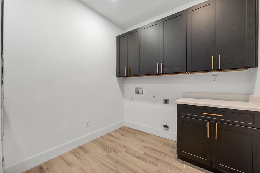 Washroom with hookup for an electric dryer, cabinet space, washer hookup, wood tiled floors, and gas dryer hookup Washroom with hookup for an electric dryer, cabinet space, washer hookup, wood tiled floors, and gas dryer hookup