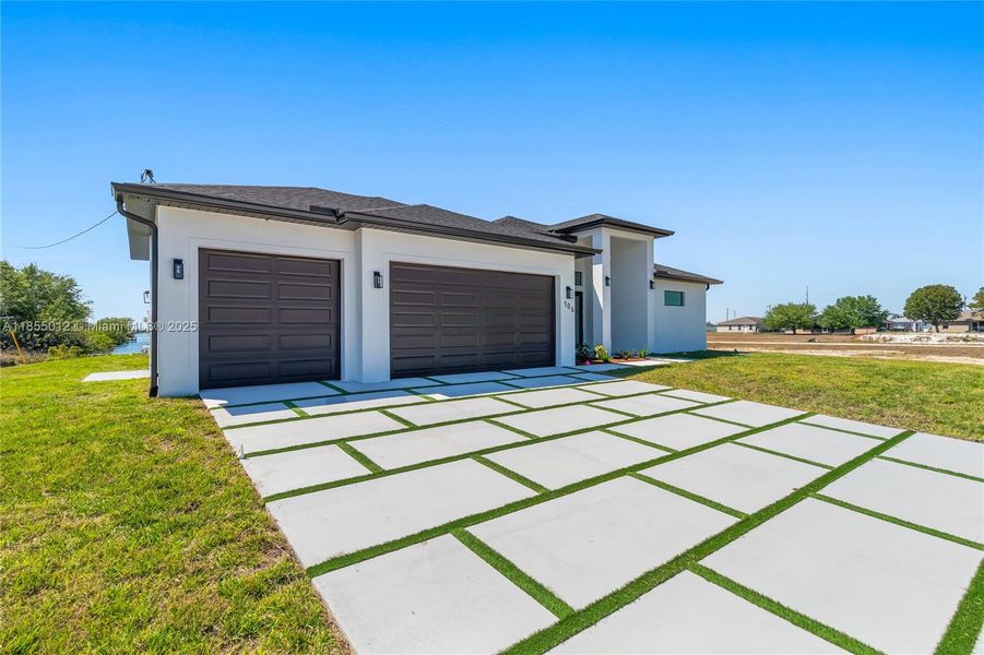 View of front of property featuring an attached 3 car garage, custom driveway.