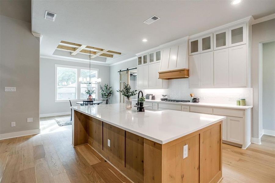 Kitchen with recessed lighting, coffered ceiling, light wood-type flooring, a spacious island, and crown molding Kitchen with recessed lighting, coffered ceiling, light wood-type flooring, a spacious island, and crown molding