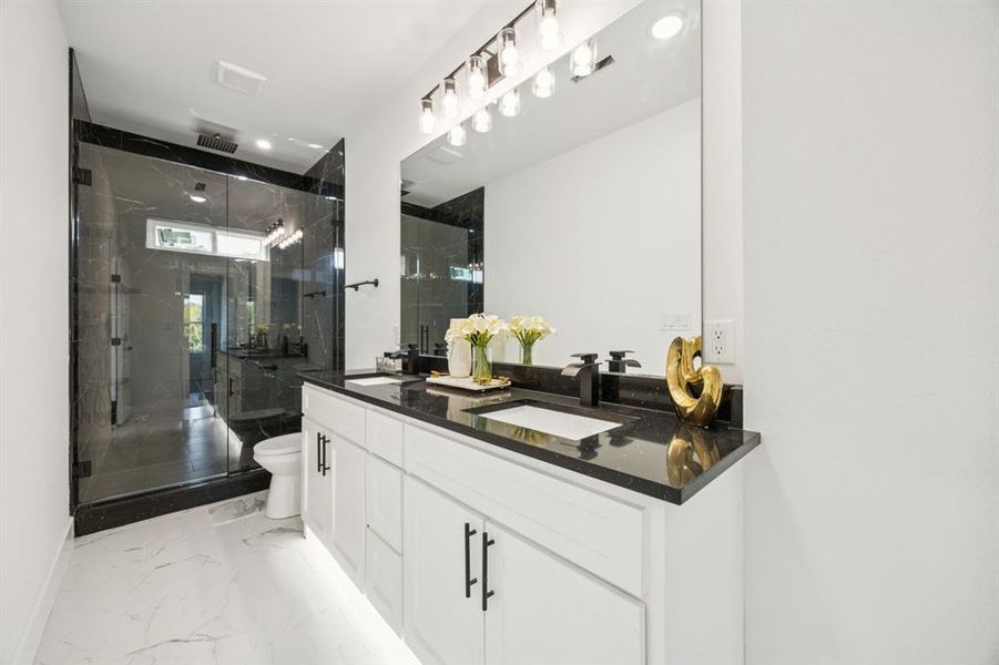 Bathroom with double vanity, a marble finish shower, and light marble finish flooring