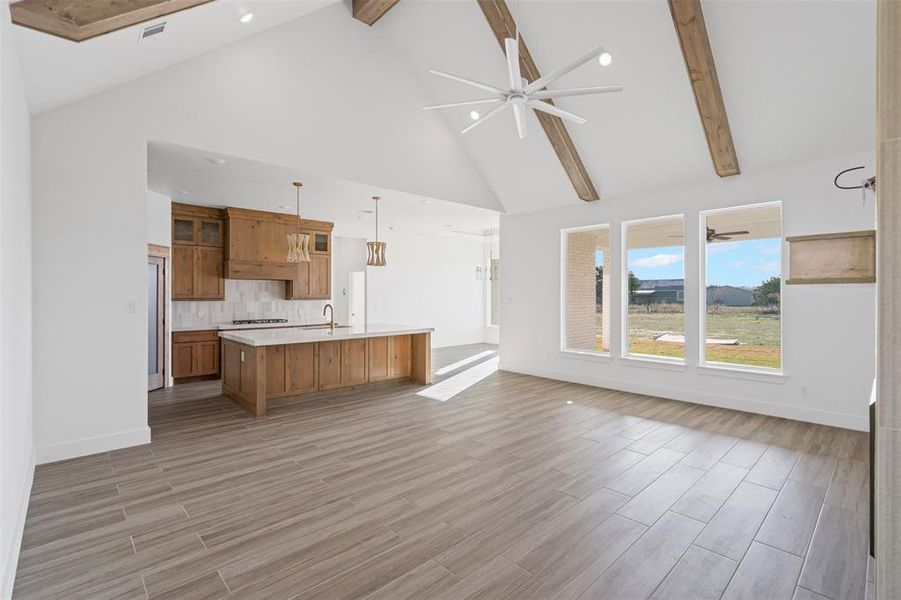 Unfurnished living room with beam ceiling, high vaulted ceiling, and light hardwood / wood-style flooring