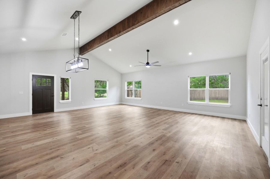 A spacious great room features vaulted ceilings, rich wood flooring, and ample natural light from multiple windows. A spacious great room features vaulted ceilings, rich wood flooring, and ample natural light from multiple windows.
