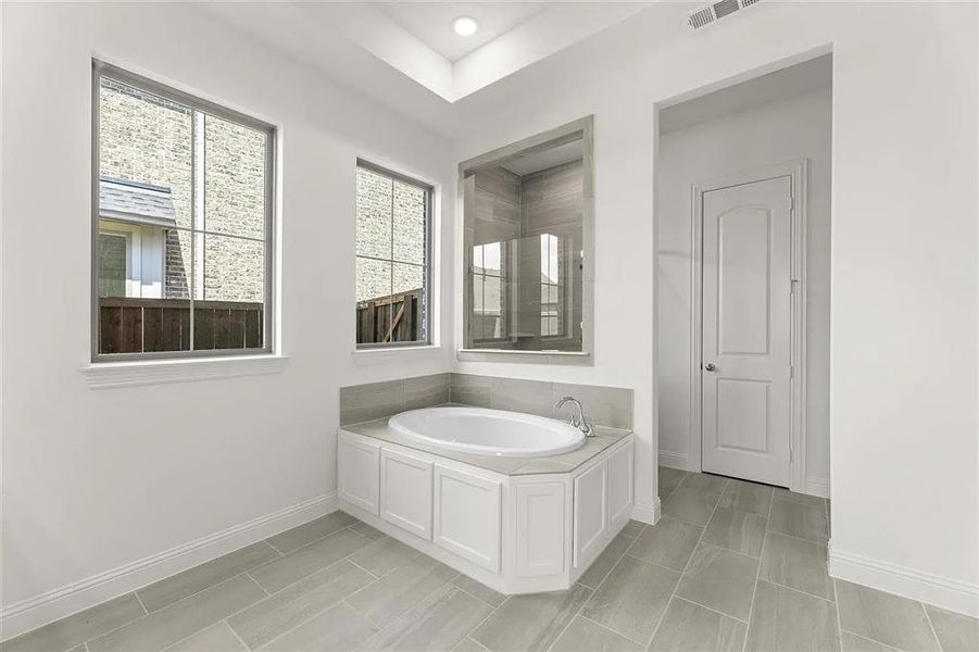 Bathroom with a tub to relax in and tile patterned flooring