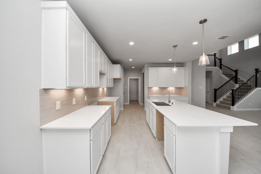 This kitchen is truly a chef's dream! This haven Boasts high ceilings, recessed & pendant lighting, stained wood cabinets, granite countertops, stainless steel appliances, a modern tile backsplash.  All of this overlooks your expansive family room, creating a perfect space for culinary delights and family gatherings.