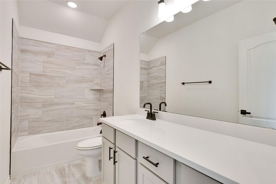 Bathroom featuring shower / tub combination, vanity, recessed lighting, and lofted ceiling