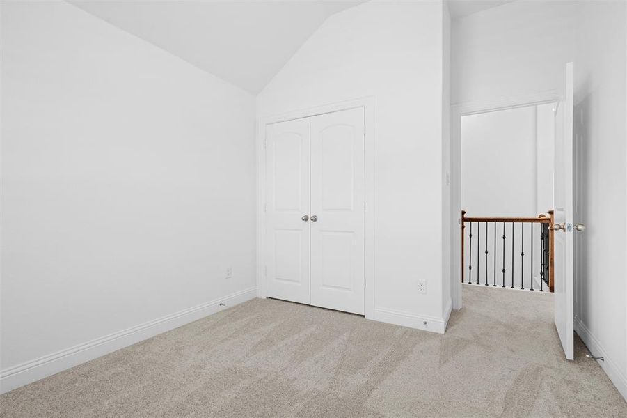 Unfurnished bedroom featuring lofted ceiling, light colored carpet, and a closet