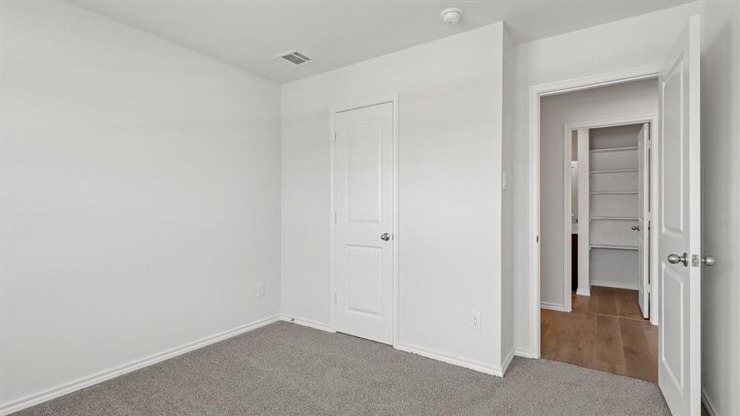Neutral-toned room featuring a soft gray carpet, white walls, and a white interior door