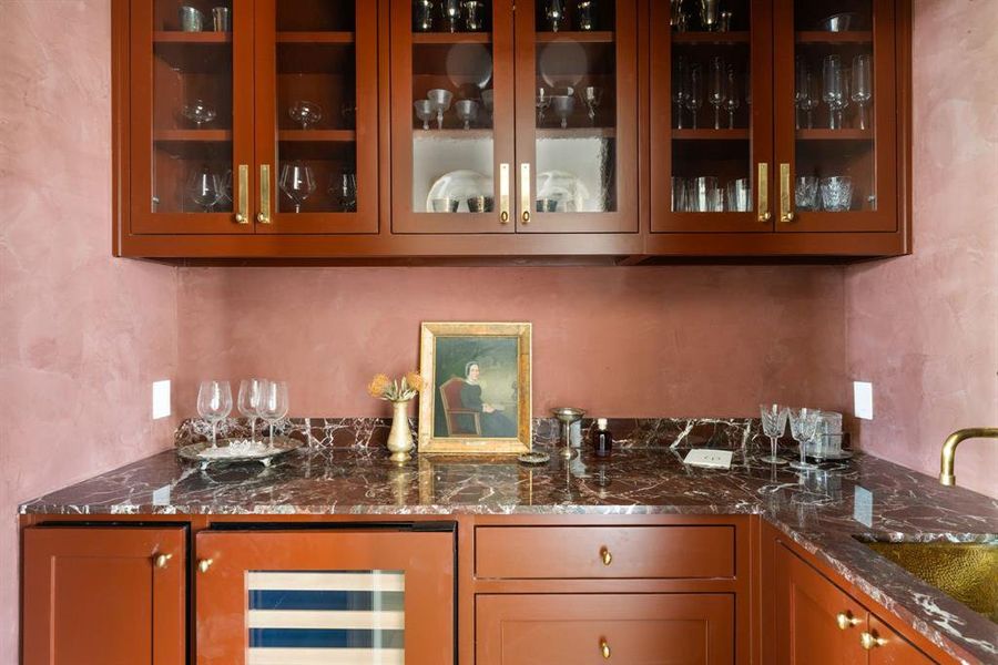 Indoor wet bar featuring wine cooler, glass insert cabinets, and dark stone countertops