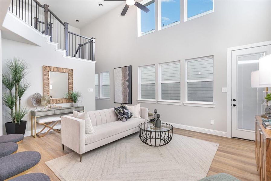 Living room with a towering ceiling, light hardwood / wood-style floors, and ceiling fan