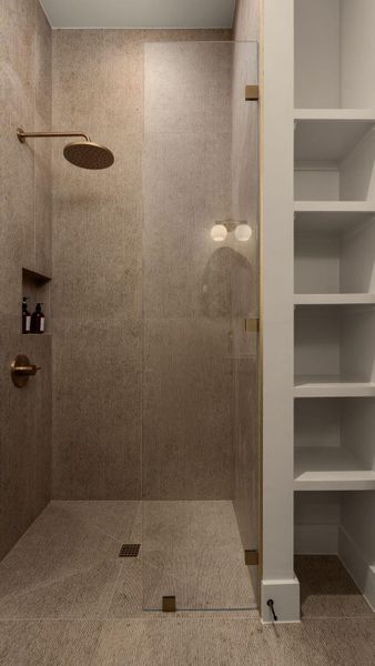 Step into a generously sized shower with a glass enclosure and built-in shelving, offering a blend of modern design and utility. Step into a generously sized shower with a glass enclosure and built-in shelving, offering a blend of modern design and utility.